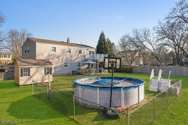 view of pool featuring a fenced in pool, fence, a shed, a lawn, and an outbuilding