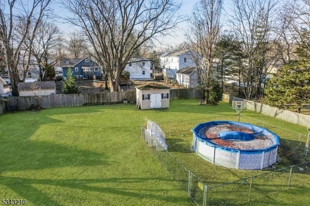 view of yard with an outbuilding, a fenced in pool, a storage unit, and a fenced backyard