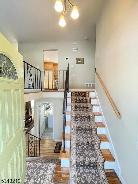 stairway with visible vents, baseboards, a notable chandelier, and wood finished floors