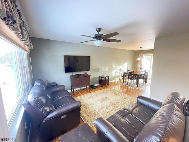 living area with a ceiling fan, wood finished floors, and baseboards