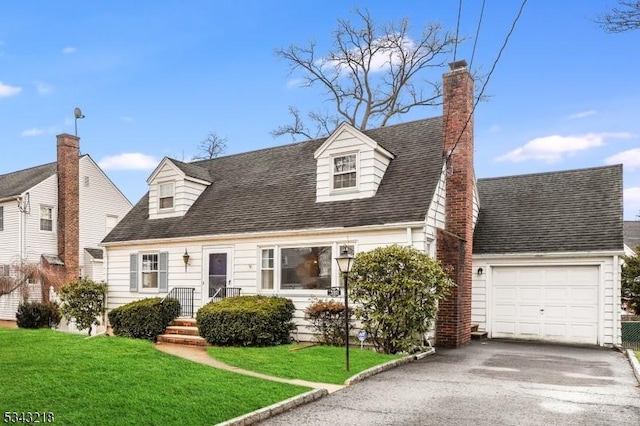 cape cod-style house featuring a front lawn, roof with shingles, a chimney, a garage, and driveway