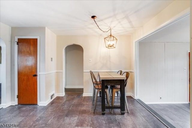 dining room featuring an inviting chandelier, visible vents, arched walkways, and baseboards