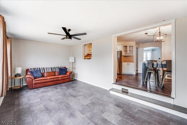 living area featuring baseboards, arched walkways, and a ceiling fan