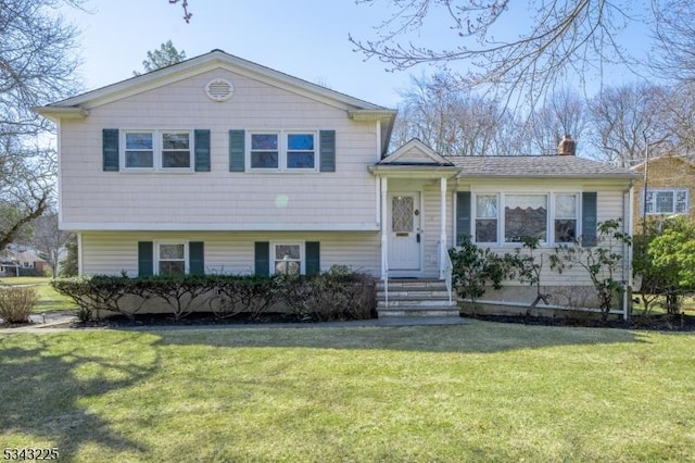 tri-level home with a chimney and a front lawn