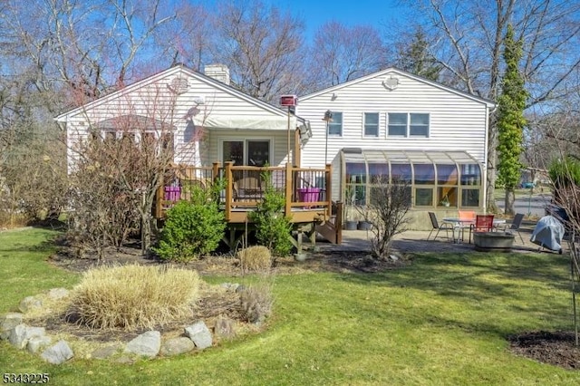 back of house featuring a yard, a deck, a chimney, and a patio area