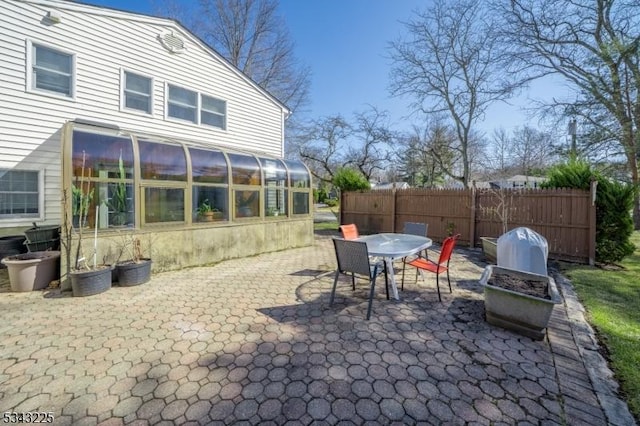 view of patio / terrace featuring a sunroom, outdoor dining space, and fence