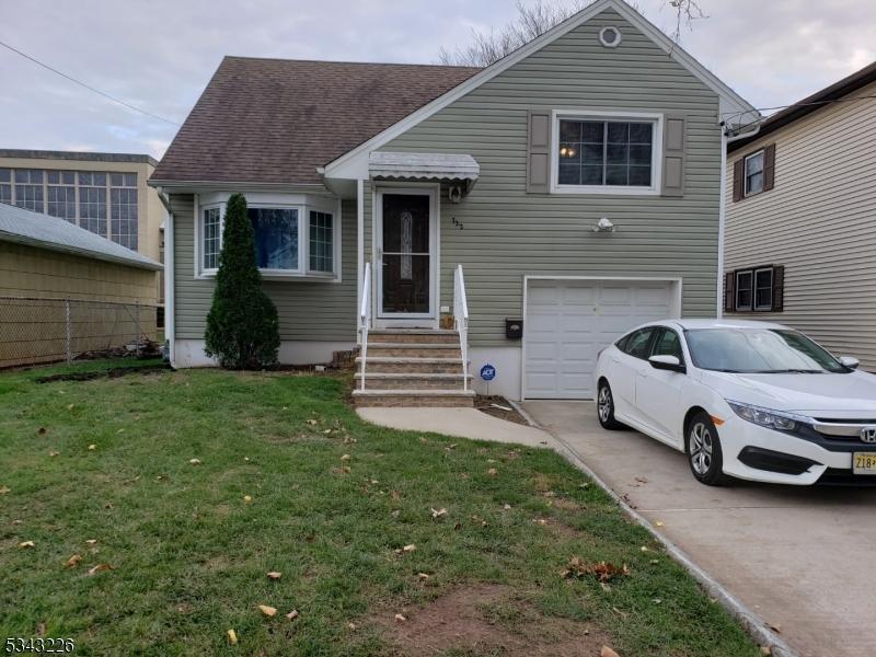 split level home with a garage, concrete driveway, a front yard, and a shingled roof