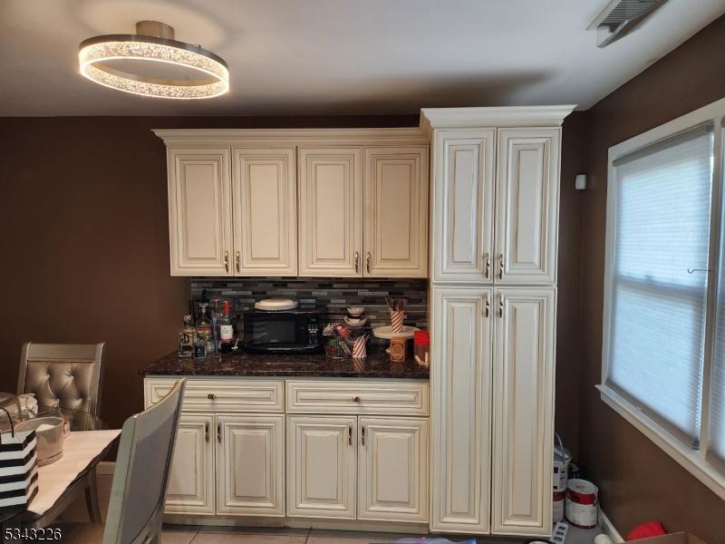 kitchen with visible vents, tasteful backsplash, and dark stone counters