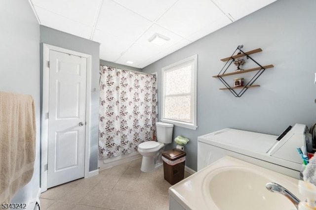 bathroom with a sink, tile patterned flooring, a paneled ceiling, toilet, and washing machine and dryer