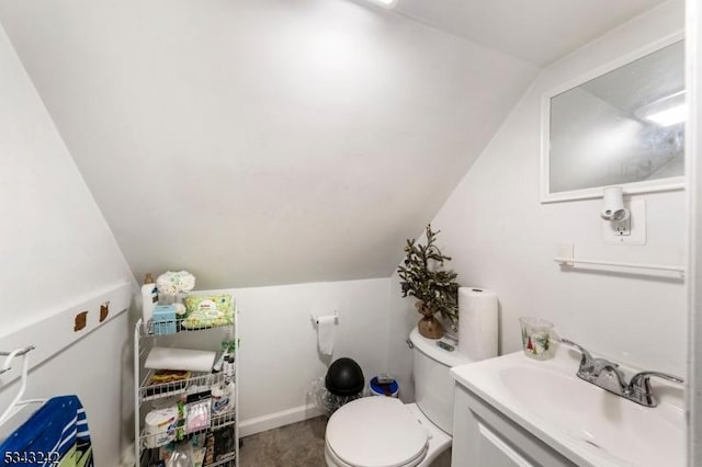 bathroom featuring toilet, vanity, baseboards, and vaulted ceiling