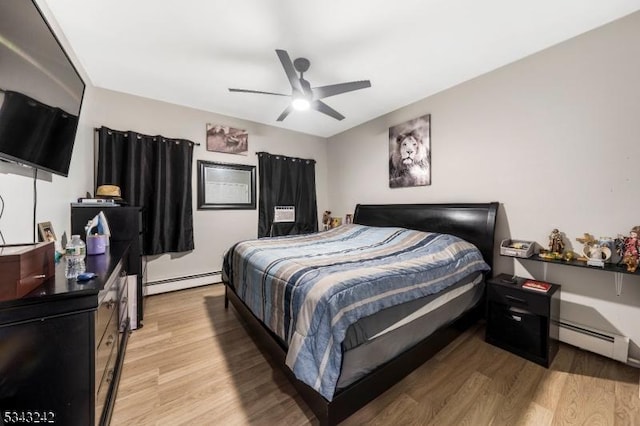 bedroom featuring a ceiling fan, a baseboard heating unit, and light wood-style floors