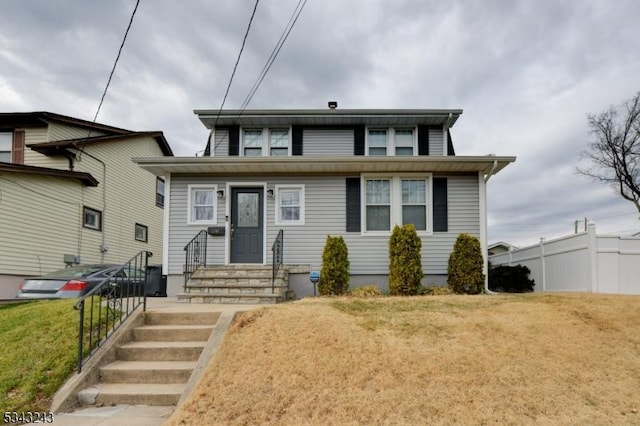 view of front of house with entry steps, a front yard, and fence