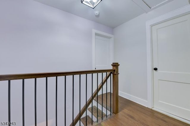 corridor featuring an upstairs landing, baseboards, and wood finished floors