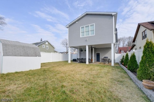 rear view of property with a lawn, a fenced backyard, a storage shed, an outdoor structure, and a patio area