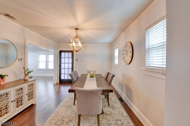 dining area featuring visible vents, a notable chandelier, dark wood-style floors, crown molding, and baseboards