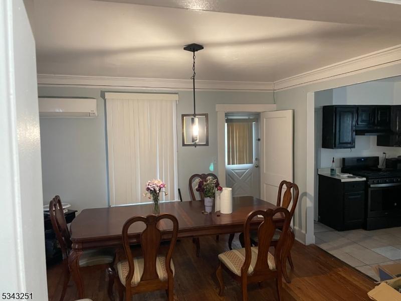 dining space featuring crown molding, light wood-style flooring, and a wall mounted AC