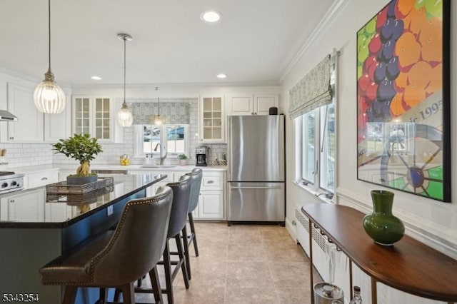 kitchen with a sink, decorative backsplash, white cabinetry, and freestanding refrigerator