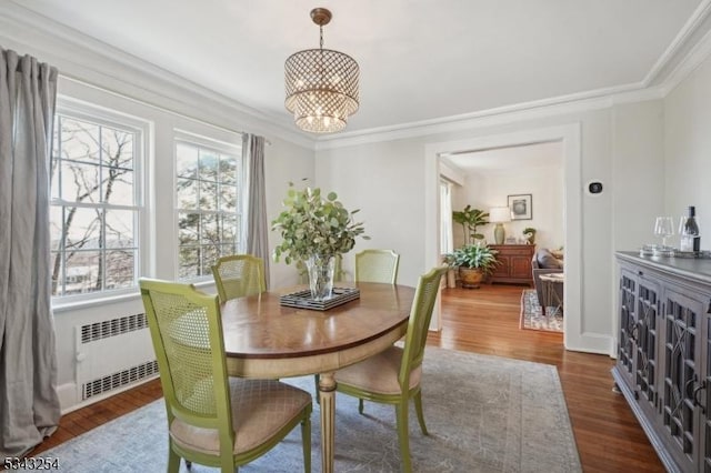 dining room featuring an inviting chandelier, dark wood-style flooring, radiator heating unit, and ornamental molding