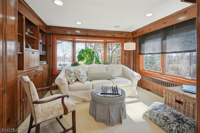 living area with radiator, recessed lighting, wood walls, and light carpet