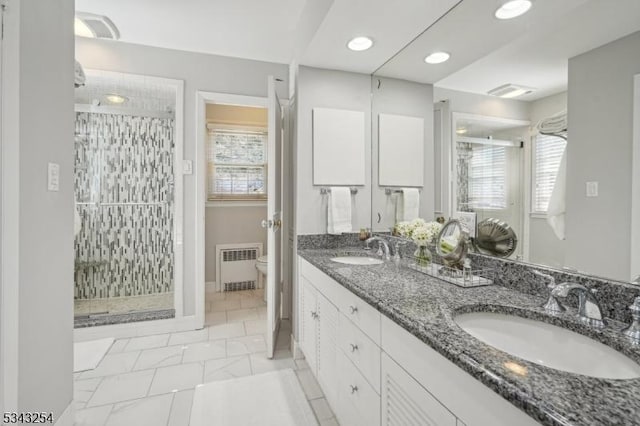 bathroom with a sink, radiator, toilet, and a stall shower