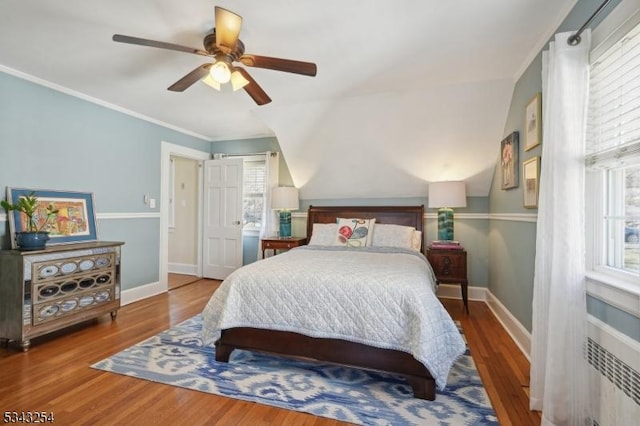 bedroom featuring a ceiling fan, crown molding, wood finished floors, and baseboards