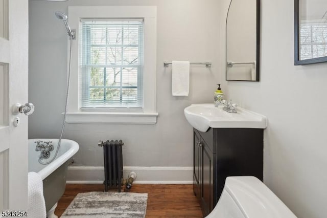 full bathroom with a freestanding tub, wood finished floors, radiator, baseboards, and vanity