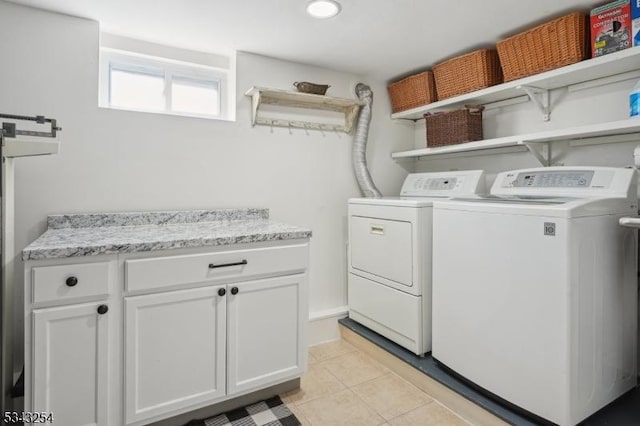 laundry area featuring light tile patterned floors, cabinet space, and separate washer and dryer