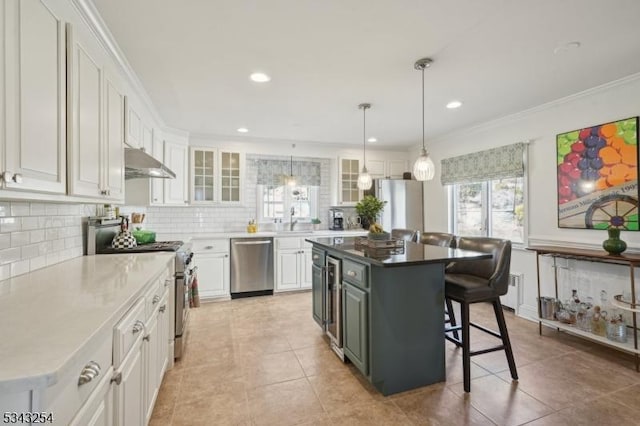 kitchen with a breakfast bar, decorative backsplash, stainless steel appliances, white cabinetry, and a sink