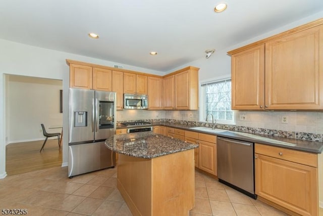 kitchen with light tile patterned floors, a kitchen island, a sink, stainless steel appliances, and tasteful backsplash