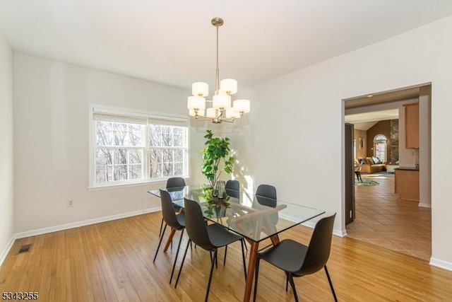 dining room featuring light wood-type flooring, baseboards, visible vents, and an inviting chandelier