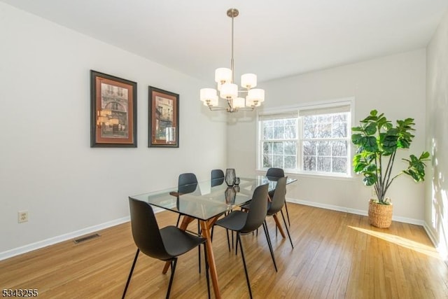 dining area with visible vents, an inviting chandelier, light wood-type flooring, and baseboards