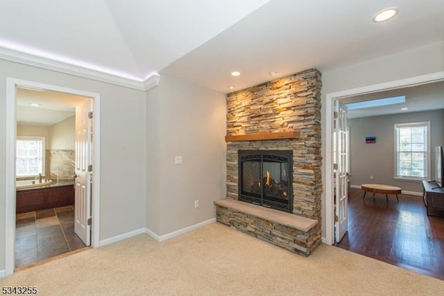 unfurnished living room with carpet, baseboards, recessed lighting, a stone fireplace, and vaulted ceiling