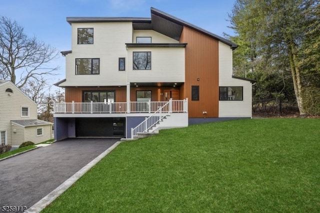 rear view of house featuring aphalt driveway, an attached garage, and a lawn