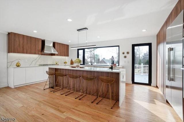 kitchen featuring a wealth of natural light, modern cabinets, wall chimney exhaust hood, and light countertops