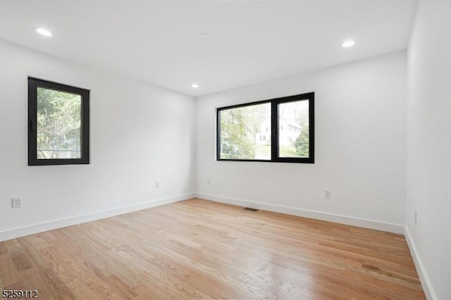 empty room featuring recessed lighting, baseboards, and light wood finished floors