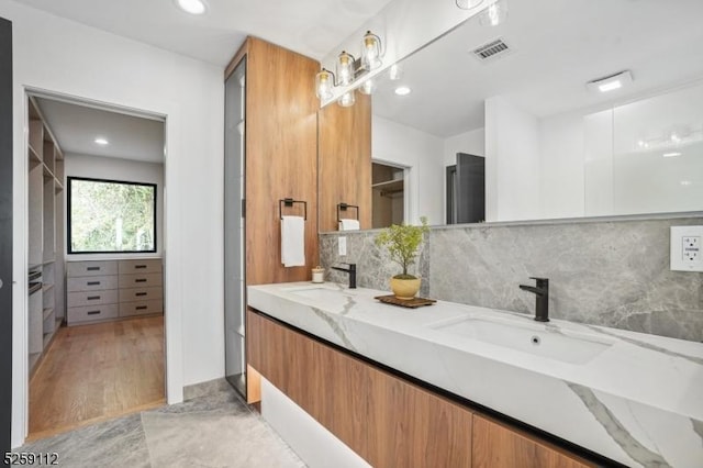 full bath with a sink, visible vents, tasteful backsplash, and double vanity