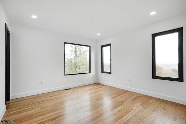 unfurnished room featuring visible vents, recessed lighting, light wood-type flooring, and baseboards