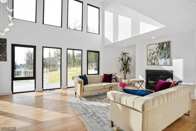 living area with light wood-style floors and a glass covered fireplace