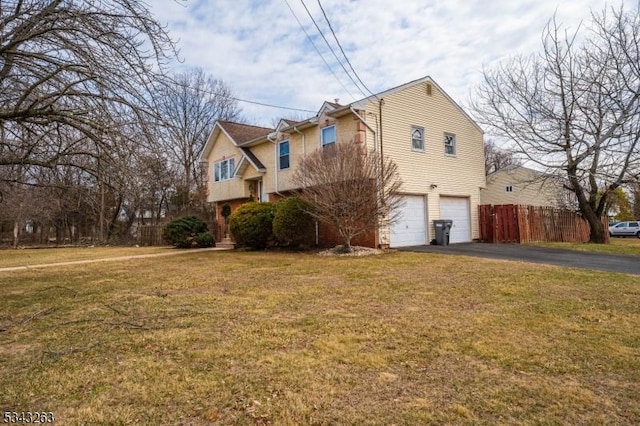 view of home's exterior with fence, an attached garage, driveway, and a lawn