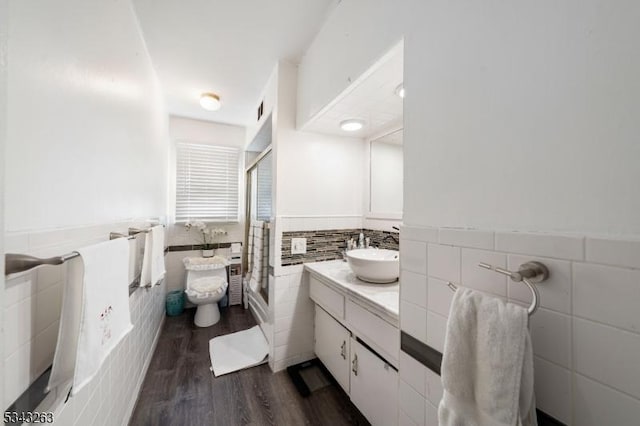 bathroom featuring a wainscoted wall, a shower stall, tile walls, and wood finished floors