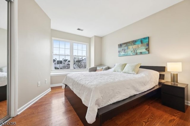 bedroom featuring visible vents, baseboards, and wood finished floors