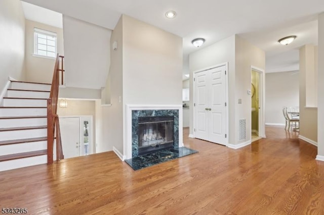 unfurnished living room with wood finished floors, recessed lighting, stairway, a fireplace, and baseboards