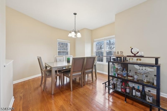 dining area featuring an inviting chandelier, wood finished floors, and baseboards