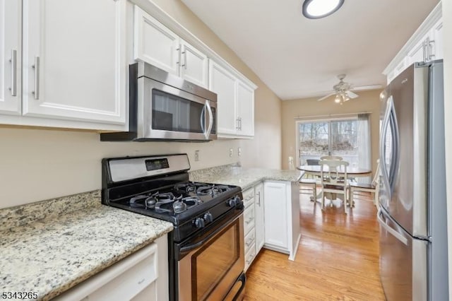 kitchen with ceiling fan, light wood-type flooring, light stone counters, appliances with stainless steel finishes, and white cabinetry