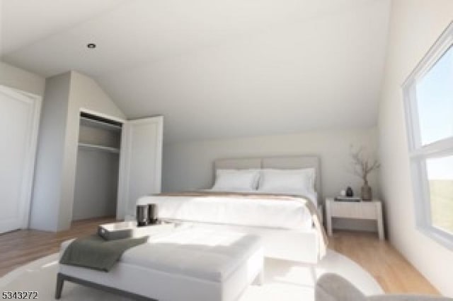 bedroom featuring a closet, light wood finished floors, and vaulted ceiling