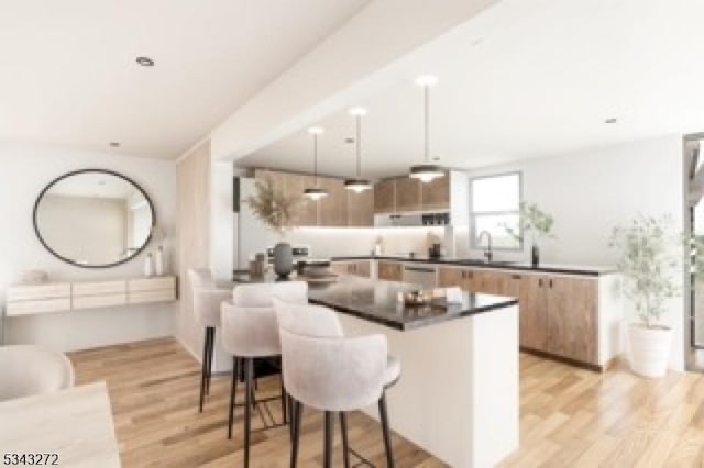 kitchen featuring dark countertops, light wood finished floors, a breakfast bar, hanging light fixtures, and modern cabinets