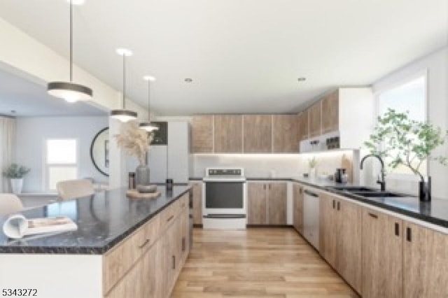 kitchen with light brown cabinets, light wood-style flooring, a sink, stove, and modern cabinets