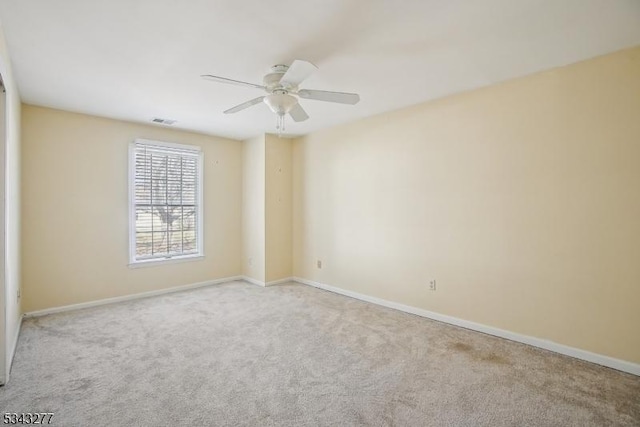 carpeted empty room with a ceiling fan, baseboards, and visible vents