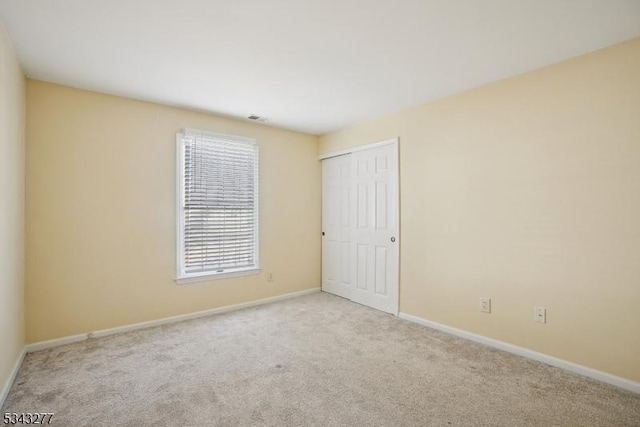 empty room featuring baseboards, carpet floors, and visible vents