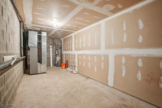 unfinished basement featuring heating unit, electric water heater, and concrete block wall